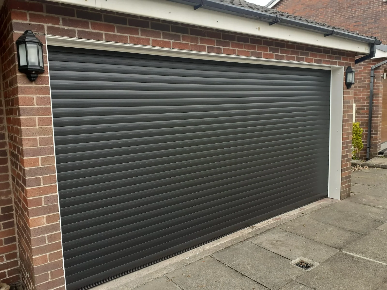 Anthracite insulated roller garage door fitted to a brick garage in Bolton